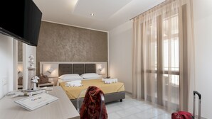 A hotel room with a bed, a desk with a computer, a suitcase, and a window with sheer curtains. - La Dimora del Pescatore (San Vito Lo Capo)