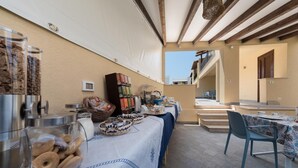 A buffet setup with various food items and beverages, including a coffee machine, bowls of pastries, and a selection of books. - La Dimora del Pescatore (San Vito Lo Capo)