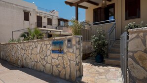 A stone wall with a sign, a staircase, and a building with balconies. - La Dimora del Pescatore (San Vito Lo Capo)