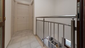 A narrow hallway with a metal railing, a closed door at the end, and a window at the far end. - La Dimora del Pescatore (San Vito Lo Capo)
