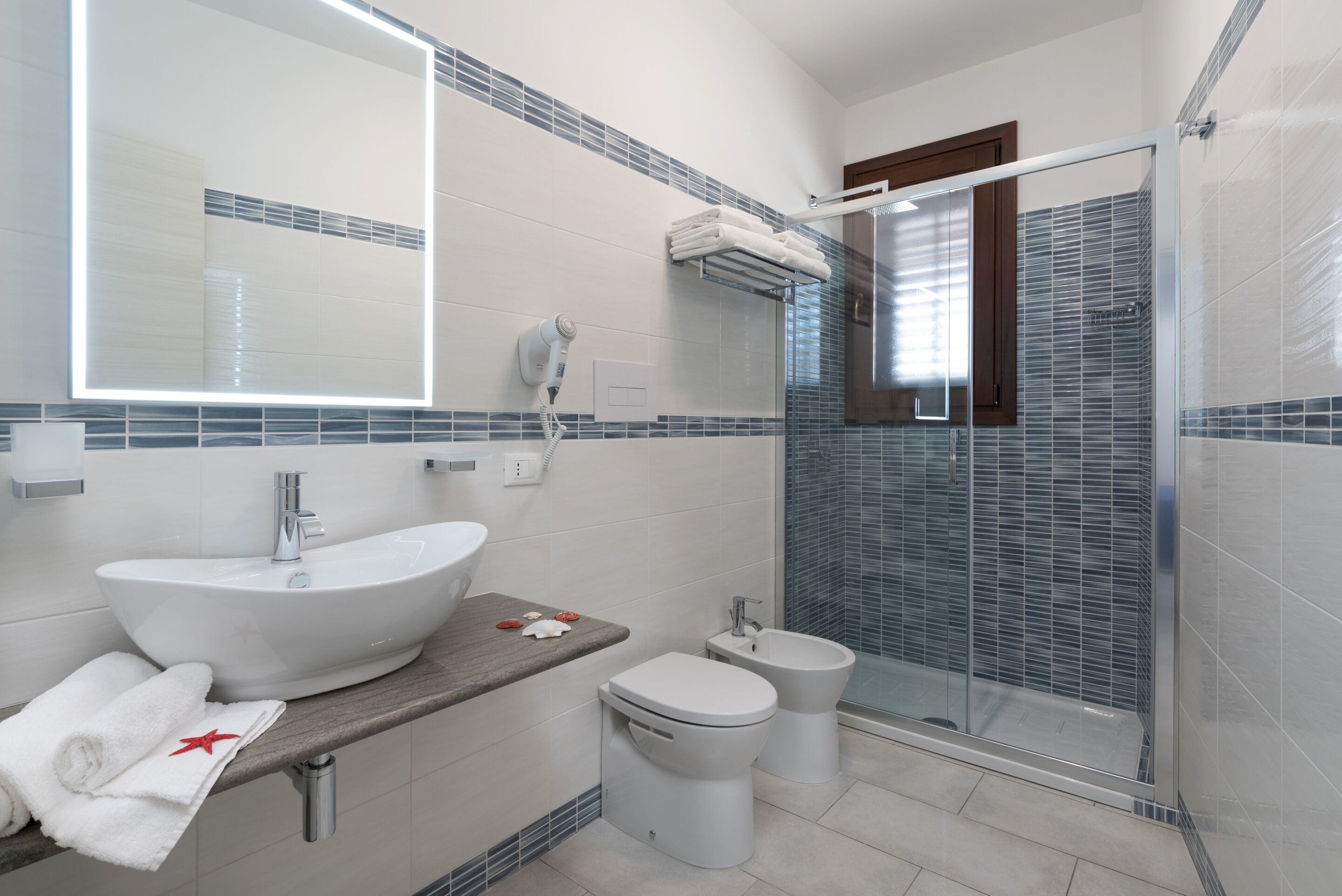 A modern bathroom with a large sink, toilet, and glass shower enclosure.
