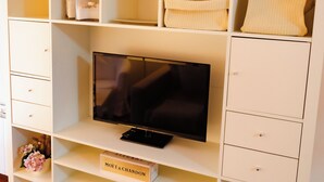 A white entertainment unit with a flat-screen TV, shelves, and drawers. - Apartamentos Costa Norte (San Vicente de la Barquera)