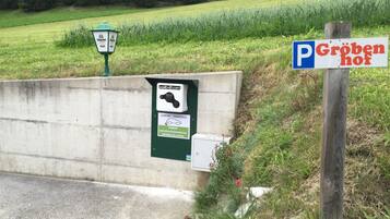 A parking sign with a green lamp post and a concrete barrier.