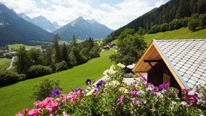 A mountain cabin with a sloped roof, surrounded by vibrant flowers and a lush green landscape. - Gasthof Gröbenhof (Fulpmes)