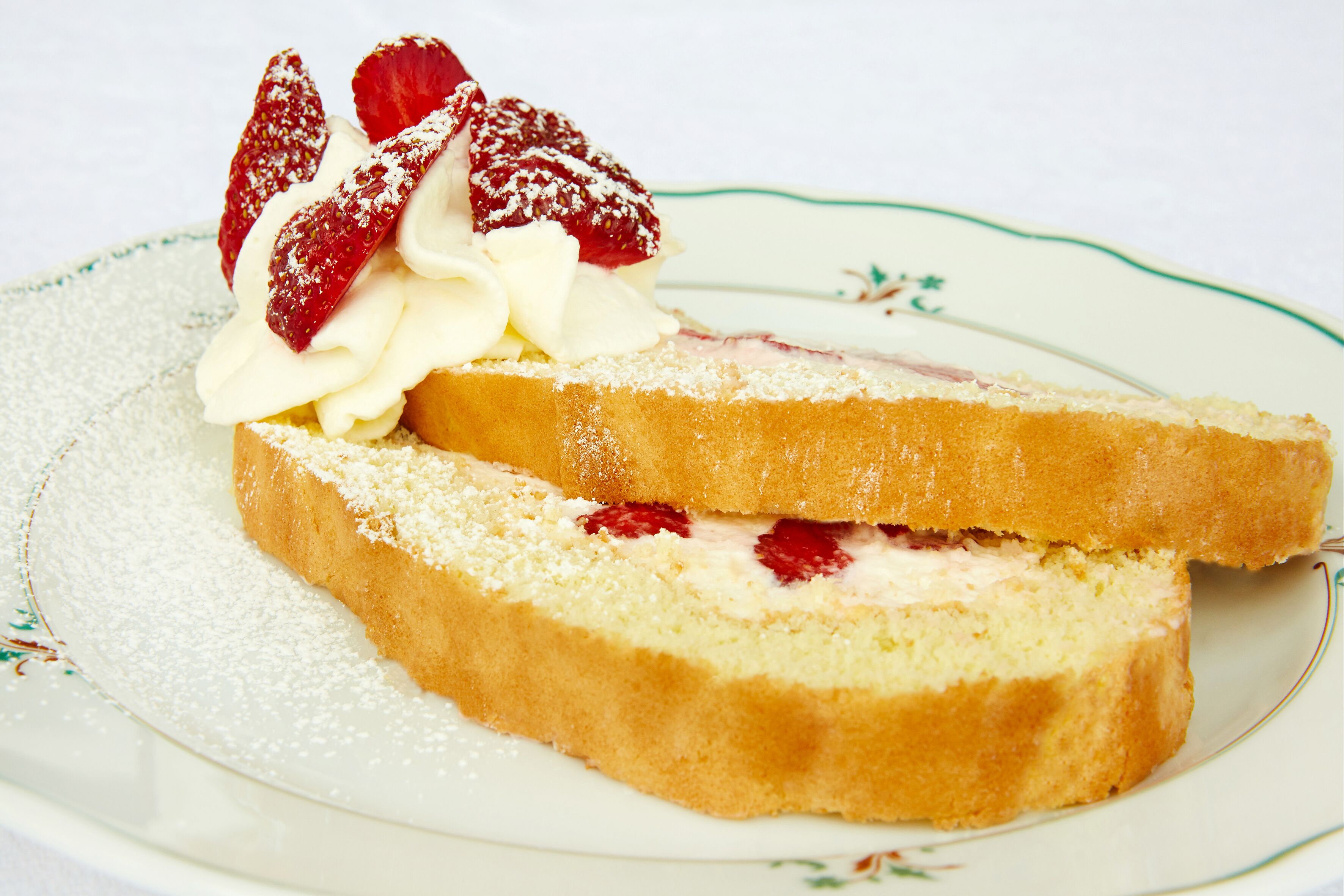 A slice of cake with whipped cream and strawberries on a plate.