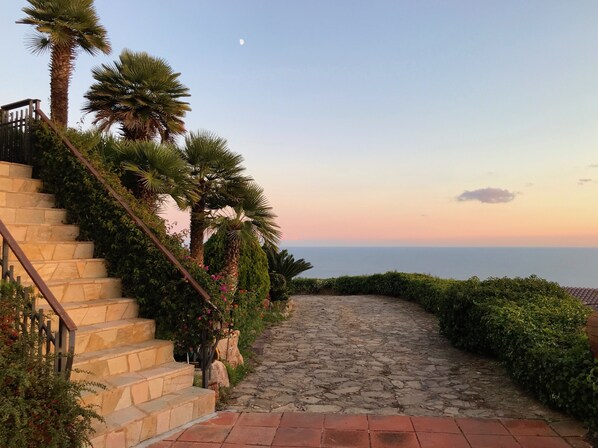 A stone staircase leading to a balcony with a view of the sea.
