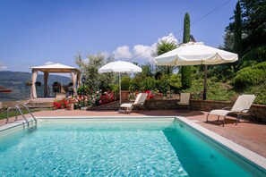 Un espace piscine agrémenté d’un gazebo, de chaises longues et de parasols.