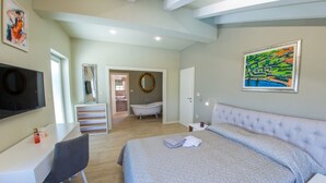 Une chambre à coucher comprenant un lit, un bureau, une chaise, une coiffeuse, une baignoire et un téléviseur.