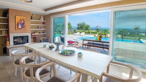 Un vaste espace dédié à la salle à manger, offrant une vue sur une piscine et comprenant un coin salon extérieur.