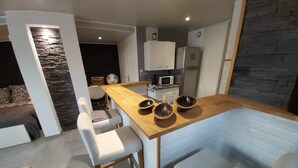 A modern kitchen with a wooden countertop, white chairs, and a built-in bench. - Studio Villa Nui GH (Cuers)