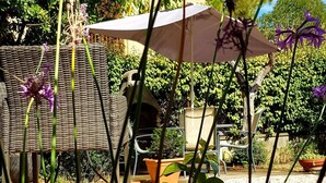 A patio area with wicker furniture, a table, and chairs under a large umbrella. - Studio Villa Nui GH (Cuers)