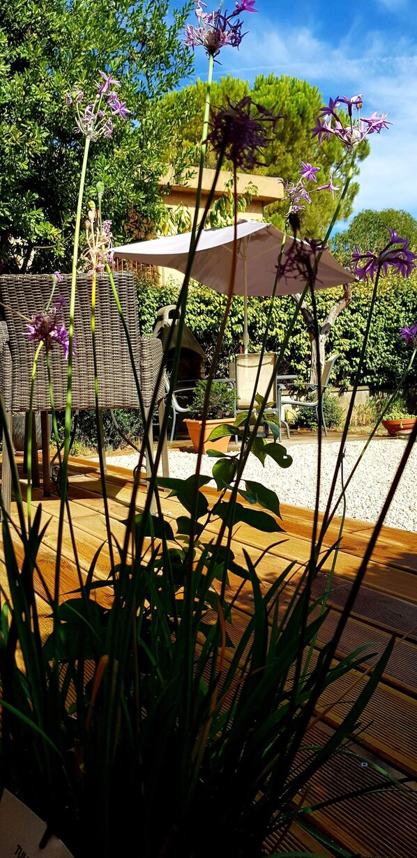 Ein Patio mit Korbmöbeln, einem Tisch und Stühlen unter einem großen Sonnenschirm.