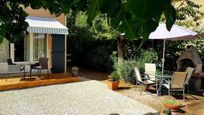 A patio area with a wooden deck, outdoor seating, and a small table. - Studio Villa Nui GH (Cuers)
