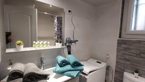 A modern bathroom with a grey vanity, a mirror, a hairdryer, a toilet, and a window. - Studio Villa Nui GH (Cuers)