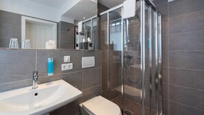 Ein modernes Badezimmer mit einer Duschkabine, einem Waschbecken und einer Toilette.