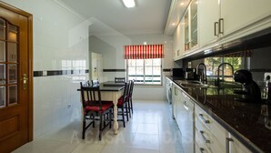 Una cocina moderna con armarios blancos, encimera negra y un comedor con mesa y sillas.