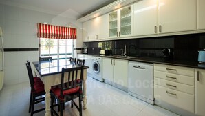 Una cocina moderna con armarios blancos, encimera negra y un valance de ventana a rayas rojas y blancas.