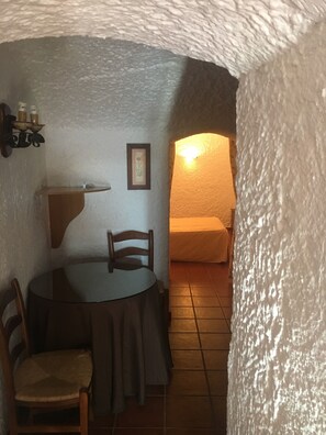 Ein gemütlicher Essbereich mit einem runden Tisch, Stühlen und einer an der Wand befestigten Ablage mit Kerzen.
