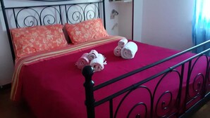 A bed with a red bedspread, two pillows, and rolled towels. - B&B Casa Mucci (Sestola)