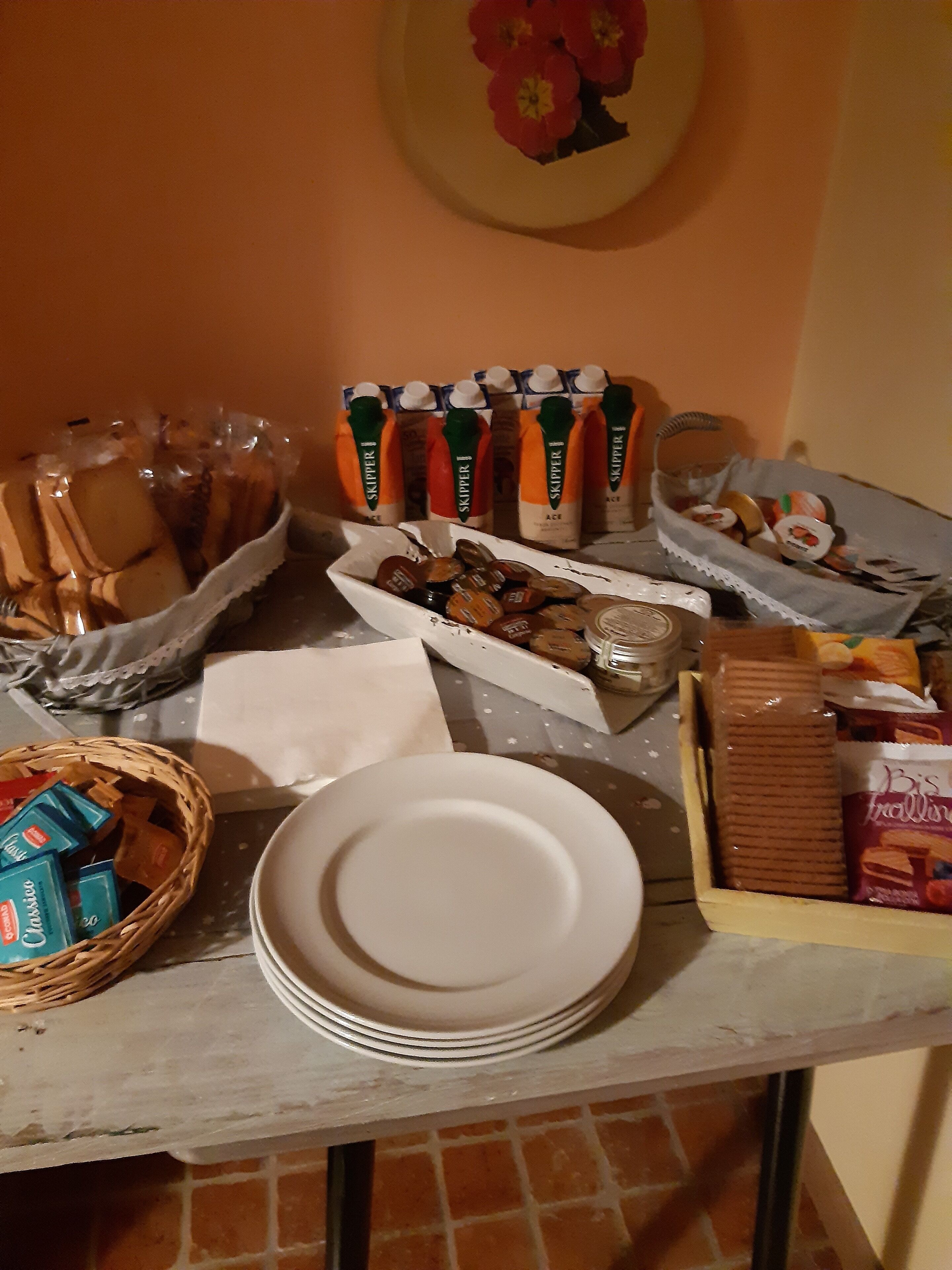 Et bord med forskellige spisemuligheder, heriblandt kager, et brødkurv og juice.