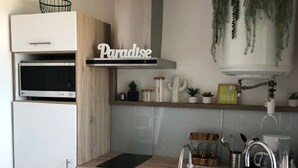 Eine moderne Küche mit weißen Schränken, einem eingebauten Ofen, einer Edelstahl-Spüle und Pendelleuchten.