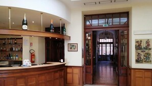 Un espace bar avec des meubles de rangement en bois, un comptoir et des bouteilles exposées sur des étagères. Un extincteur est posé sur le comptoir.