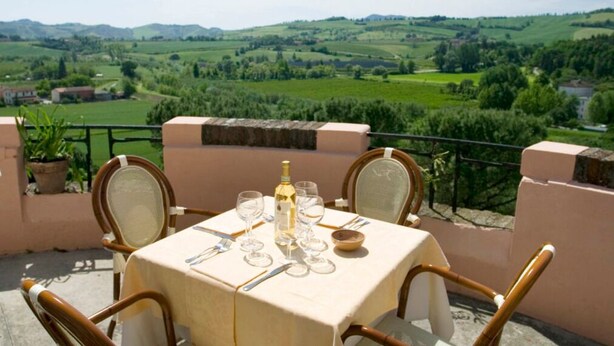 Une table dressée à l’extérieur, avec vue sur des collines ondoyantes.