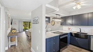 Una cocina moderna con armarios azul oscuro, encimera de granito y ventilador de techo.