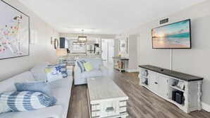 Un salón espacioso con sofá, mesa de centro y televisor montado en la pared.