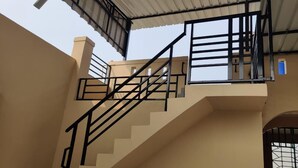A staircase with black railings leading to a covered upper level. - Sukhmani Homestays. Your own space in a private bungalow. (KOLKATA)