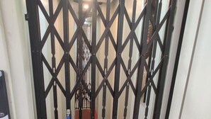 A narrow stairway with a metal gate, a red carpet, and a ceiling light fixture. - Sukhmani Homestays. Your own space in a private bungalow. (KOLKATA)