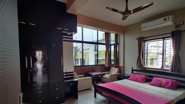 A bedroom with a bed, a desk, a chair, a wardrobe, and a ceiling fan. - Sukhmani Homestays. Your own space in a private bungalow. (KOLKATA)