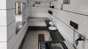 A narrow, tiled kitchen with a built-in oven and a sink. - Sukhmani Homestays. Your own space in a private bungalow. (KOLKATA)