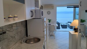 Una cucina moderna con lavello, pensili e vista mare da un balcone.