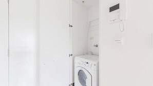 Een kleine, witte wasruimte met een voorlader wasmachine en een ingebouwde droger.