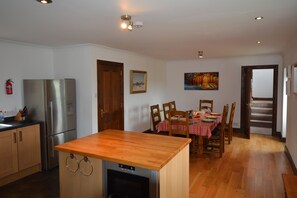 A kitchen with a wooden countertop, stainless steel refrigerator, and a dining area with a table set for four.