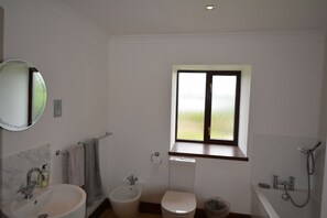 A bathroom with a sink, bidet, toilet, and bathtub.