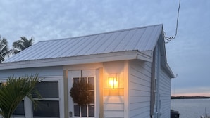 A small, single-story house with a white exterior and a red doormat. - Matlacha Sunset Cottage (Matlacha)