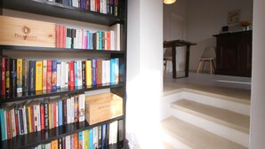 A bookshelf filled with books, a wooden box labeled "Poliziano," and a staircase leading to a room.