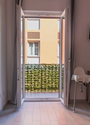 Quarto com porta de vidro deslizante que dá para uma varanda com barreira vegetal.