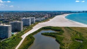 Eine Luftaufnahme einer Küstenstadt mit Strand, Hochhäusern und einem Fluss.
