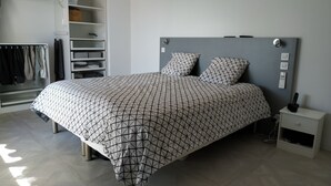 Un dormitorio con cama, mesita de noche, armario y estantería empotrada.
