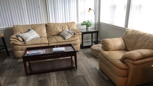 A living room with a beige leather sofa, a wooden coffee table, and a small side table with a plant.