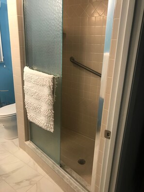 Een bad/douchecombinatie, handdoeken, toiletpapier