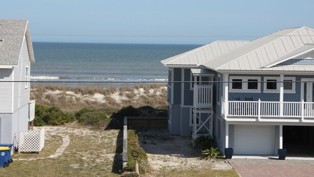 A coastal house with a garage, a balcony, and a view of the ocean.