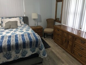 Une chambre à coucher comprenant un lit, une table de chevet, une chaise, une commode et un miroir.