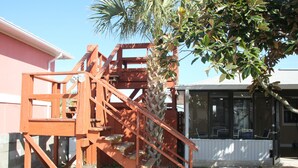 A wooden staircase leading to a deck area with a palm tree nearby.