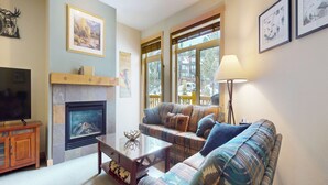 Una sala de estar con chimenea, un sofá, un televisor y una lámpara.