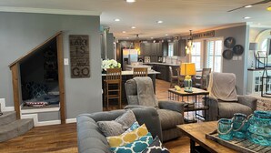 A spacious living room with a gray sofa, wooden coffee table, and a kitchen in the background. - Lakefront property with pool and lighthouse with amazing views of the lake, . (Granbury)