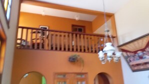 Ein mehrstöckiger Innenraum mit Balkon, einer Kristallleuchtre und einer Tür mit rundbogigem Fenster.